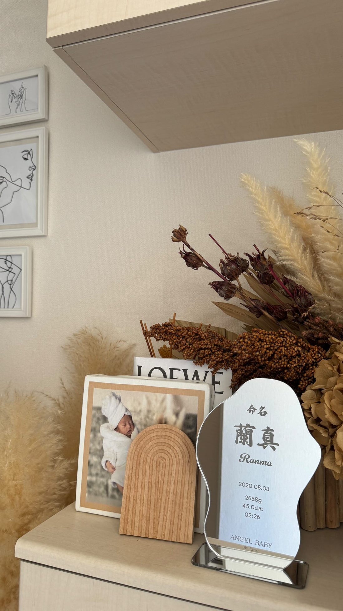 写真立てや花と一緒に棚へ飾ったミラー命名書